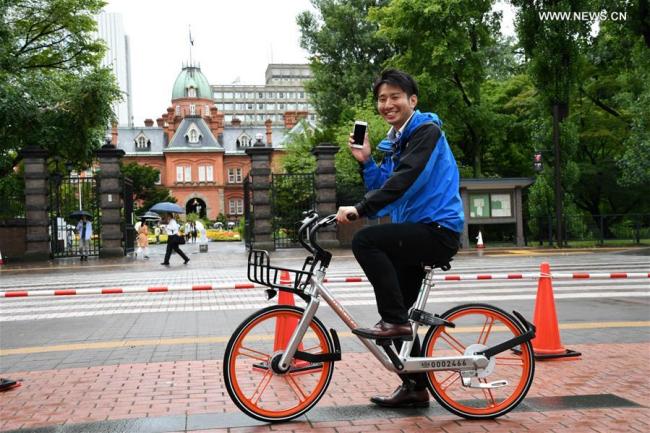 A TV reporter tries out a shared bicycle in Sapporo, Japan, on Aug. 22, 2017. [Photo: Xinhua/Hua Yi]