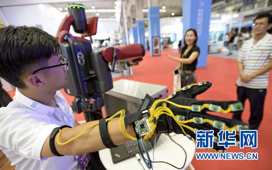 An engineer is presenting a robot from his company to the visitors. [Photo: from Xinhua]