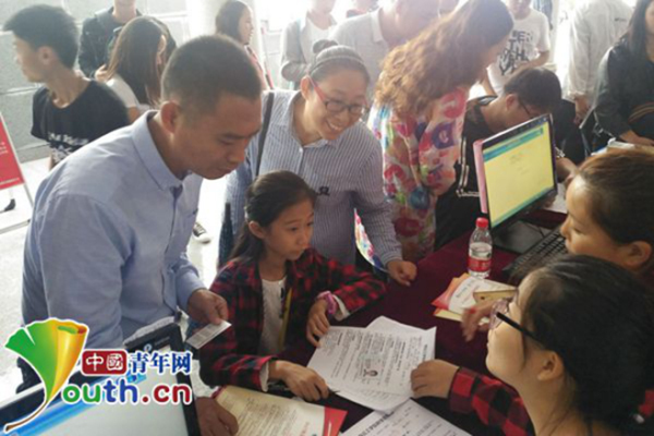 Accompanied by her parents, Zhang Yiwen registers at the registration desk at Shangqiu Institute of Technology, central China's Henan province, Sept. 10, 2017. [Photo: youth.cn]