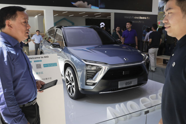 A worker, right, chats with a man as visitor look at the Nio ES8, an electric-powered SUV manufactured by Chinese automaker NIO on display at its booth during a promotion event at a shopping mall in Beijing, Monday, Sept. 11, 2017. [Photo: AP/Andy Wong]