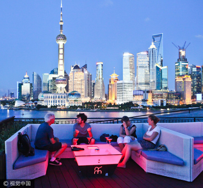 A group of international visitors rest on a rooftop in Waitan (the Bund), Shanghai on July 30, 2012. [Photo: VCG]