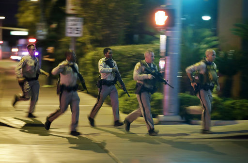 Police run to cover at the scene of a shooting near the Mandalay Bay resort and casino on the Las Vegas Strip, Sunday, Oct. 1, 2017, in Las Vegas. [Photo: AP /John Locher]