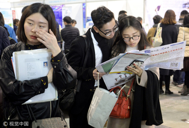 Job seekers look through information at a job fair in Hangzhou, Zhejiang Province, on Feb 28, 2017. [Photo: VCG]