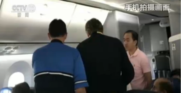 Wu Xiaobo(Right) helps assist a female passenger who passes out on his China Eastern flight on October 10, 2017. [Screenshot: CCTV]