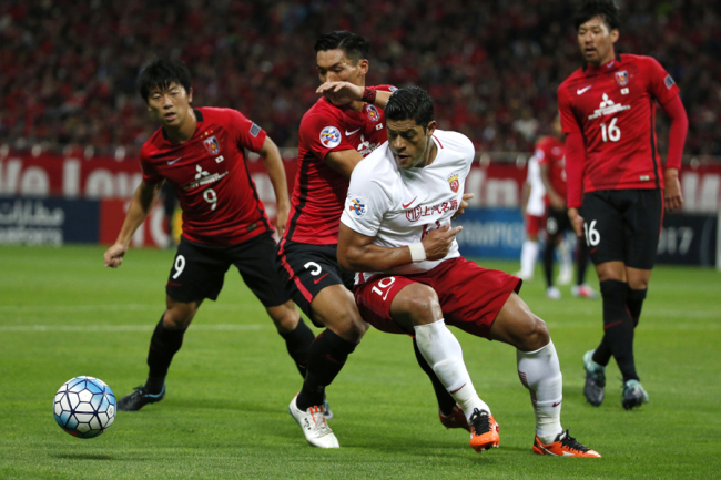 Shanghai SIPG's Hulk of Brazil, center right, and Urawa Reds' Tomoaki Makino, center left, vie for the ball in the second leg of their Asian Champions League semifinal soccer match in Saitama, Wednesday, Oct. 18, 2017. [Photo: AP]