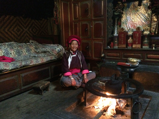 A Mosuo matriach such as this one always takes her prime place on the more important female side of the room by the family hearth,where the embers are never allowed to die out. [Photo: Courtesy of Choo Waihong]