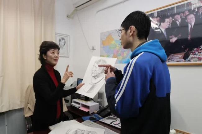 Zhou Ye communicates with a student with hearing disabilities. [File Photo: bjnews.com.cn]