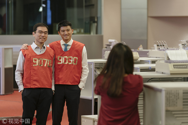 Traders wearing red trading jackets pose for a photograph on the trading floor of the Hong Kong Stock Exchange, operated by Hong Kong Exchanges & Clearing Ltd. (HKEX), in Hong Kong, China, on Tuesday, Oct. 24, 2017. HKEX will shut its iconic Trading Hall on Oct. 27, 31 years after opening the space in the heart of the city's financial district. [Photo: VCG/Bloomberg via Getty Images/ Anthony Kwan]