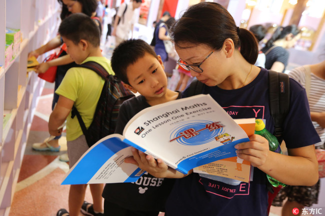 Visitors read the English version of the popular set of Shanghai Maths exercise books "One Lesson One Exercise" during the 2017 Shanghai Book Fair in Shanghai on August 22, 2017. [Photo: IC]
