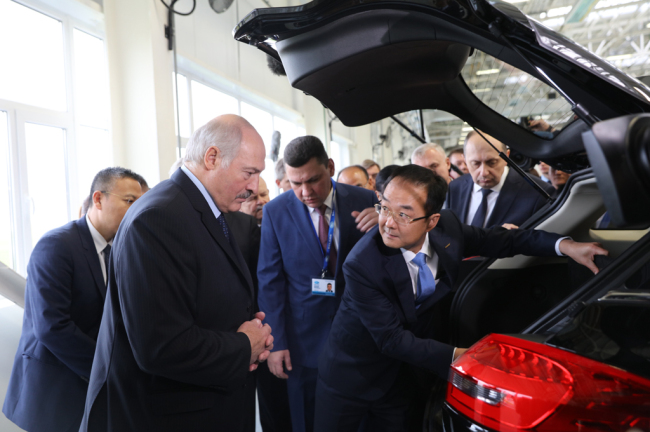 Geely Holding Group president An Conghui (front, R) introduces a newly-released car model to Belarusian President Alexander Lukashenko (front, L) in Belarus. [Photo: China Plus] 