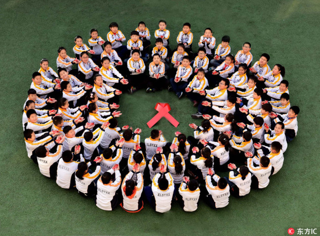 Students from a primary school in Shijiazhuang, Hebei Province sit in a circle to demonstrate red ribbons on November 30, 2017. [Photo: IC]