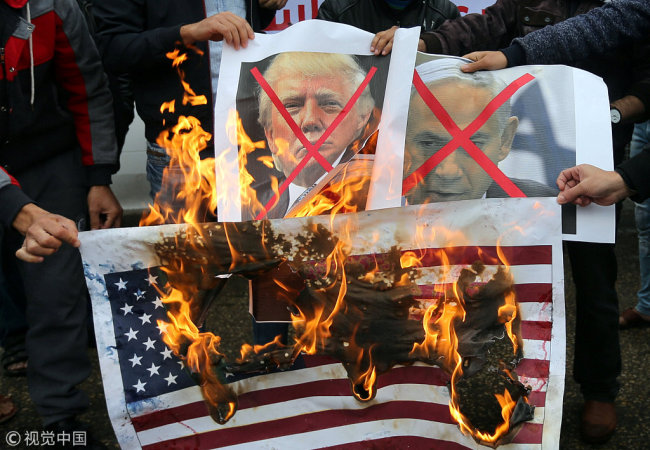 Palestinians burn posters depicting Israeli Prime Minister Benjamin Netanyahu and U.S. President Donald Trump during a protest against the U.S. intention to move its embassy to Jerusalem and to recognize the city of Jerusalem as the capital of Israel, in Rafah in the southern Gaza Strip December 6, 2017. [Photo: VCG]