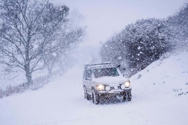 A 4x4 drives across a snow-covered road in the hills above Llangollen, north Wales, on December 8, 2017, as Storm Caroline plunges temperatures across the UK. [Photo: VCG]