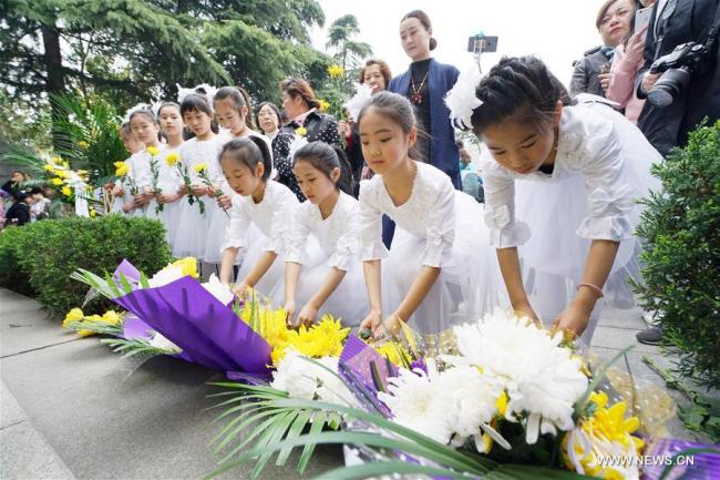 Children of a chorus lay flowers to the wall engraved with names of victims at the Memorial Hall of the Victims in Nanjing Massacre by Japanese Invaders in Nanjing, capital of east China's Jiangsu Province, April 4, 2017. [Photo: Xinhua]