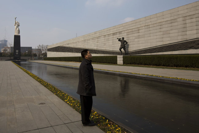 In this Feb. 11, 2014 photo, a visitor stands near sculptures at Nanjing Massacre Memorial Hall in Nanjing, in eastern China's Jiangsu province. [Photo: AP /Alexander F. Yuan]