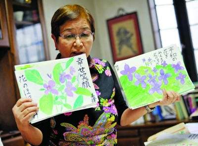 Ookado Takako shows pictures of peace symbolizing orychophragmus drawn by her students. [Photo: ifeng.com]