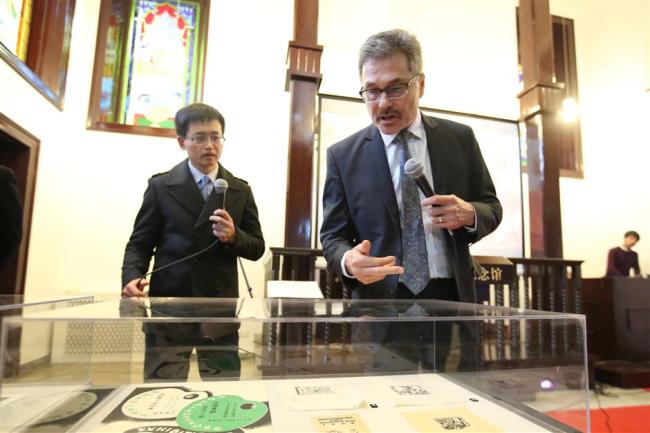 Dean Bloch (right), the son of David Bloch, the German artist who created hundreds of paintings and woodcuts about the life and customs in Shanghai during 1930s and 40s, introduces part of his father's works to visitors at the Shanghai Jewish Refugees Museum on Friday. [Photo: Shine.cn]