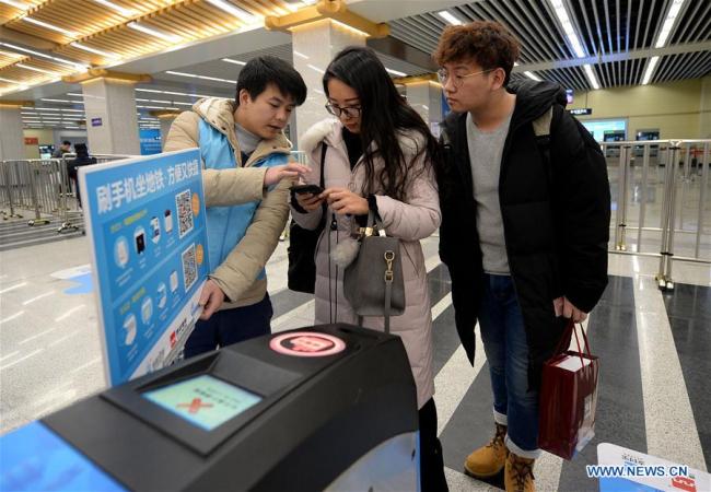 A volunteer introduces the process of taking subway with mobile payment in Dayanta Station of Xi'an, capital of northwest China's Shaanxi Province, Jan. 1, 2017. [Photo: Xinhua/Liu Xiao]