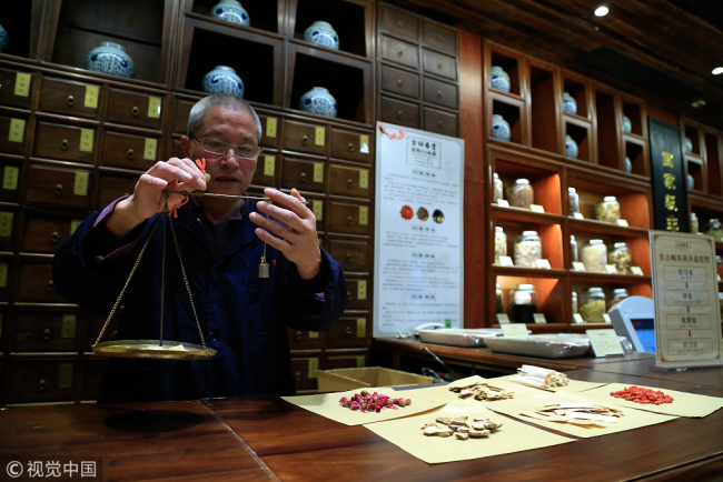 An inheritor of intangible cultural heritage weighs medicine at a TCM store in Hangzhou city, east China’s Zhejiang Province on October 23, 2017. [Photo: VCG] 
