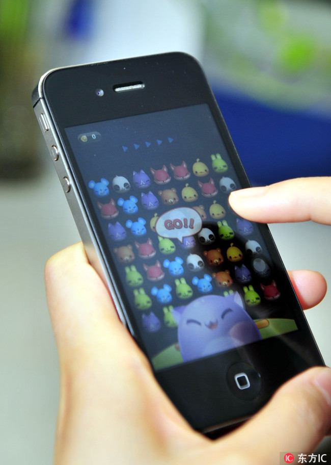 A user plays a mobile game on a iPhone 4S smartphone. [Photo: IC]