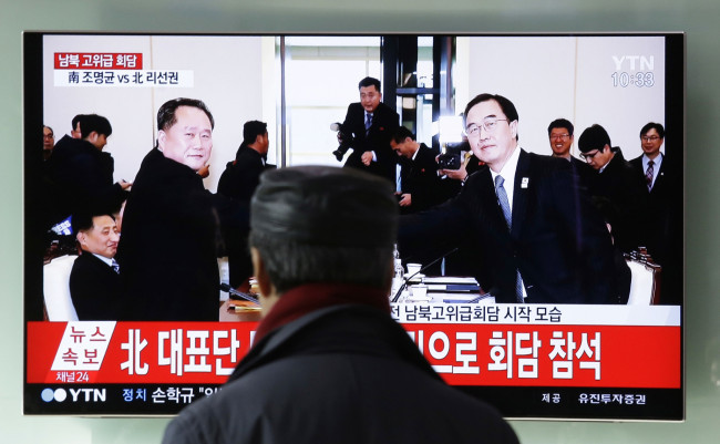A man watches a TV screen showing South Korean Unification Minister Cho Myoung-gyon, right, shakes hands with the head of North Korean delegation Ri Son Gwon during a meeting, at Seoul Railway Station in Seoul, South Korea, Tuesday, Jan. 9, 2018. [File photo: IC]