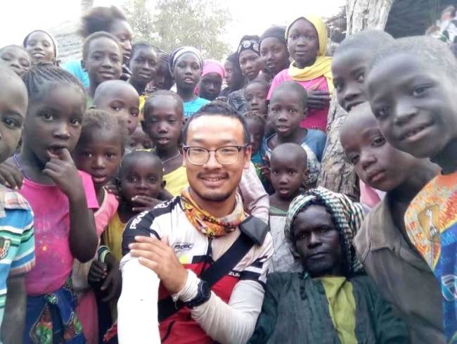Yuan Jianglei poses for a photo with his African friends. [Photo: Beijing Youth Daily]