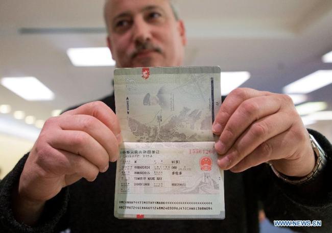 A man shows the first visa to China with validity period of 10 years he got at Chinese Visa Application Service Center in Toronto, Canada, March 9, 2015. [Photo: Xinhua]