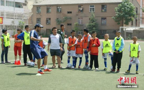 A foreign soccer coach demonstrates playing skills to students at a Chinese school. [File photo: Chinanews.com]