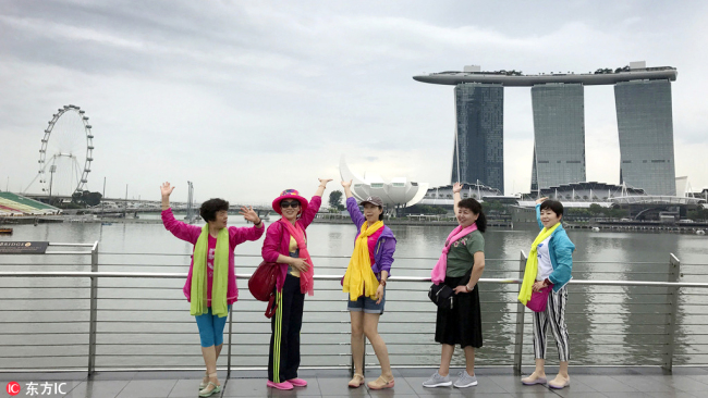 Chinese tourists pose for a group photo in front of the Marina Bay area, a popular sightseeing point for visitors in Singapore, April 3, 2017. [Photo: IC]