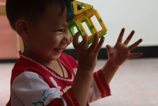 A toddler was playing toys in the Children’s Happy House. [photo: from China Plus]    