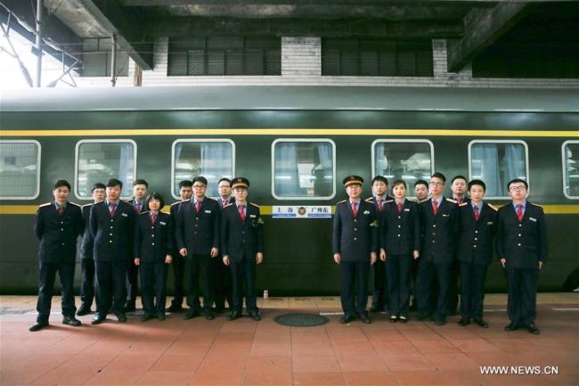 Chief conductor Kan Xiaojun and his colleagues pose for photos on a platform of Guangzhou East Railway Station in south China's Guangdong Province, Feb. 18, 2018. The 42-year-old Kan Xiaojun is a chief conductor of the train Z99. He has been on duty during the Spring Festival travel rush, also known as the Chunyun, for 12 years and has missed family reunion of the festival for seven times. Most members of Kan's team come from China's Yangtze River Delta region. Among them, the youngest attendant is 20. [Photo: Xinhua]