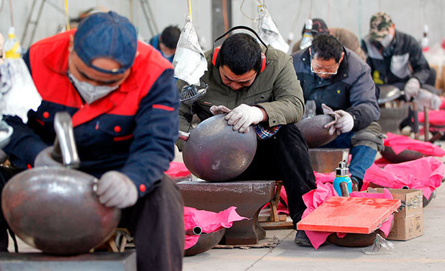 Craftsmen hammer out iron woks on Wednesday in Zhangqiu district, Jinan, Shandong province. The woks, which have boomed in popularity since they were featured on the TV show A Bite of China last month, are made using 12 steps. [Photo by Chen Zebing/China Daily]