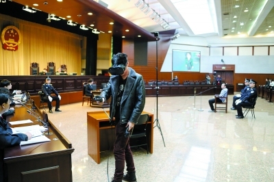 A witness wearing a pair of VR glasses and operating a hand set replicates the crime scenes he had seen on March1, 2018, at a courtroom in Beijing's No. 1 Intermediate People's Court. [Photo: Beijing Evening Post]