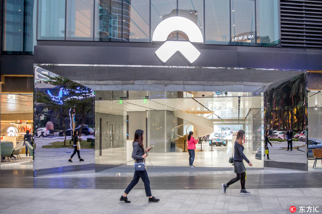 Pedestrians walk past NIO's fourth experience center, NIO House, in Guangzhou on January 23, 2018. [Photo: IC]