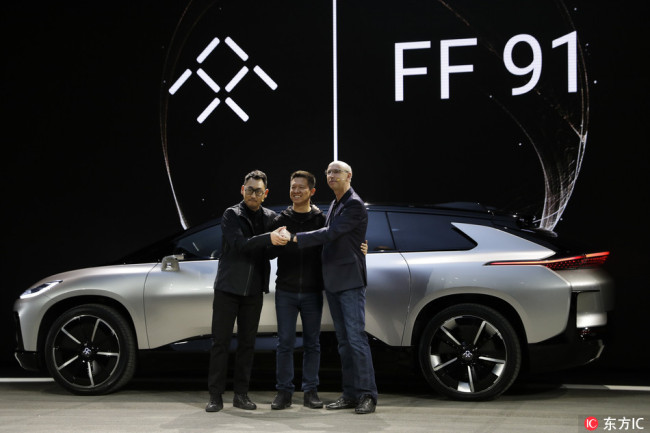 LeEco founder Jia Yueting, center, poses with Nick Sampson, Faraday Future's senior vice president of product research & development, right, and Richard Kim, vice president of design, after unveiling the FF91 electric vehicle at the CES International on January 3, 2017, in Las Vegas. [File Photo: IC]