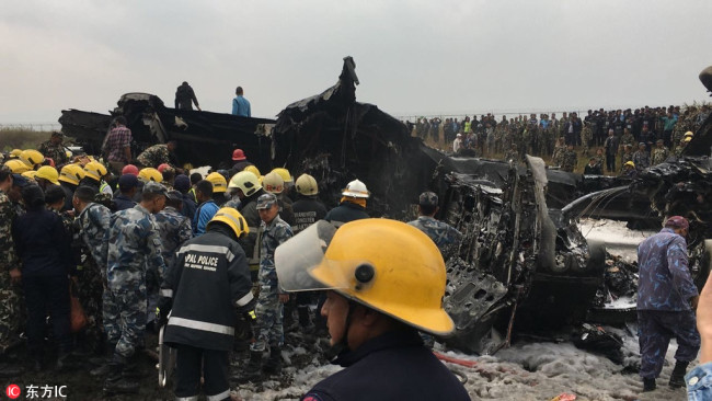 Nepalese rescuers stand near a passenger plane from Bangladesh that crashed at the airport in Kathmandu, Nepal, March 12, 2018. [Photo: IC]