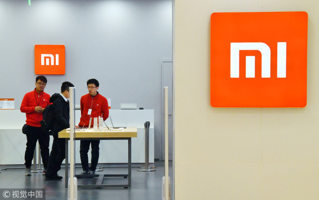 Staff introduce Xiaomi products to customer at a Xiaomi store in Beijing, March 9, 2018. [Photo: VCG]
