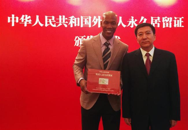 Former NBA star Stephon Marbury (L) poses with Zhang Jiandong, deputy Mayor of Beijing, during a ceremony in Beijing, capital of China, April 18, 2016. Stephon Marbury, a leading player in Beijing Duck basketball team who helped the team winning three champions in the Chinese basketball league, received his Chinese "green card", or People's Republic of China Foreigner's permanent residence card in Beijing on April 18, 2016. [File Photo: Xinhua]