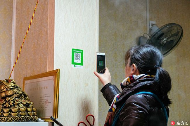 A customer pays by scanning a QR code with her WeChat app in Shaanxi Province on February 21, 2018. [File Photo: IC]