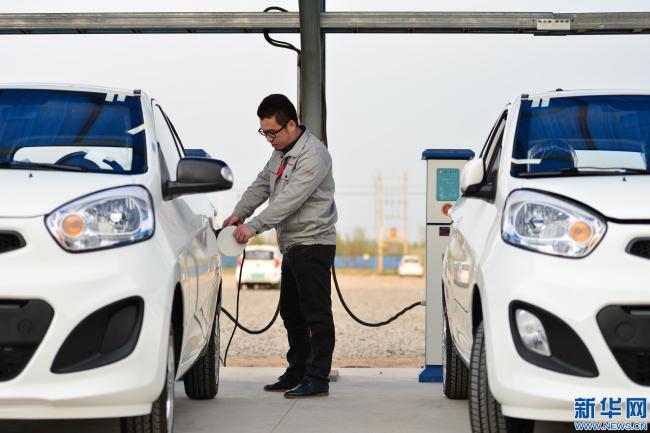 A man charges an electric car in Qinghe County, Hebei Province. [File Photo: Xinhua]