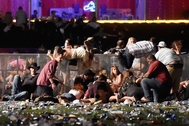 People scramble for shelter at the Route 91 Harvest country music festival after apparent gun fire was heard on October 1, 2017 in Las Vegas, Nevada. On the evening of October 1, 2017, almost 60 people were killed and more than 800 injured in a mass shooting in Las Vegas, the deadliest mass shooting in modern U.S. history. [Photo: VCG]