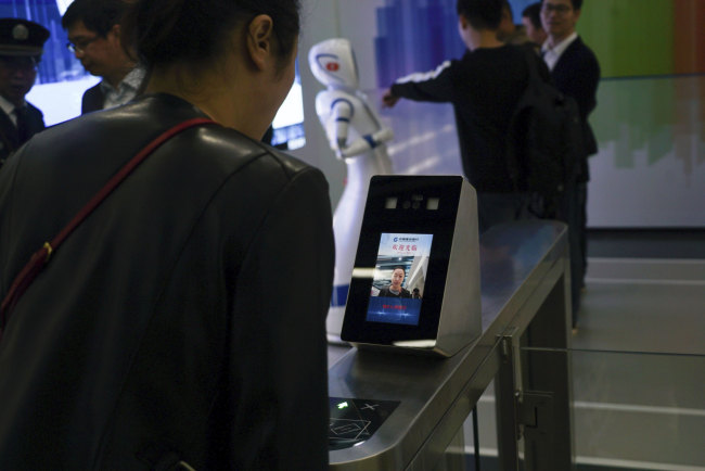 In this April 13, 2018, photo, a China Construction Bank employee demonstrates the use of face-scanning software at an automated bank in Shanghai. The outlet opened by the Beijing-based bank has been dubbed China's first "unmanned bank" and is equipped with holograms, a virtual reality room and talking robots. [Photo: AP]