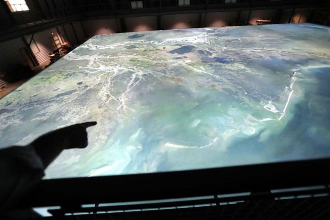In this March 29, 2018 photo, Rudy Joseph McClatchy, coastal resources program specialist for the Louisiana Coastal Protection and Restoration Authority, points out features of a replica of the lower Mississippi River, with satellite images projected onto it from above, in Baton Rouge, La. [Photo: AP/Gerald Herbert]
