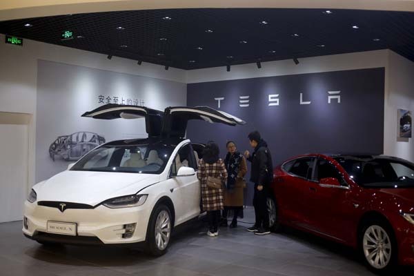 A sales person attends his customers near the Tesla electric vehicles at a showroom in Beijing, Thursday, April 5, 2018. [Photo: AP/Andy Wong]