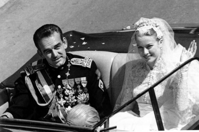 Princess Grace Kelly waves to cheering crowds as she rides with Prince Rainier III following their marriage in Monaco Cathedral on April 19, 1956. [File Photo: AP] 