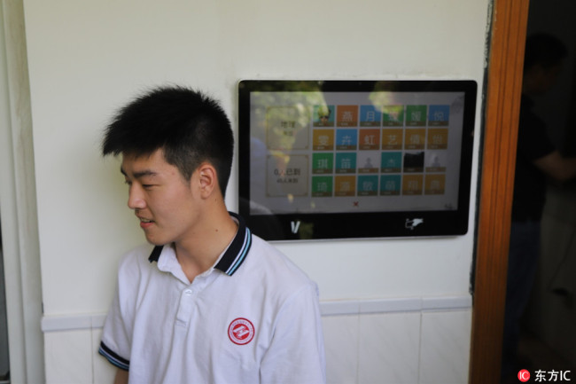 A student registers his attendance using a facial recognition camera outside a classroom at Hangzhou No. 11 High School, in Hangzhou, Zhejiang Province, on May 15, 2018. [Photo: IC]