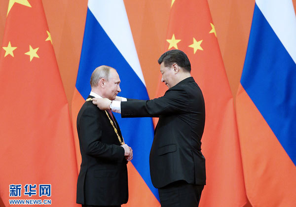 Chinese President Xi Jinping (Right) awards his Russian counterpart Vladimir Putin the first-ever Friendship Medal of the People's Republic of China at the Great Hall of the People in Beijing, capital of China, June 8, 2018. [Photo: Xinhua/Shen Hong]