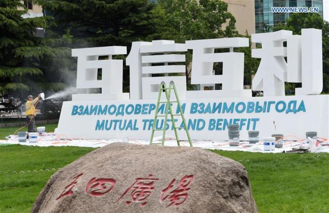 A staff member decorates a sign for the Shanghai Cooperation Organization (SCO) Qingdao Summit in Qingdao, east China's Shandong Province, June 2, 2018. [Photo: Xinhua] 