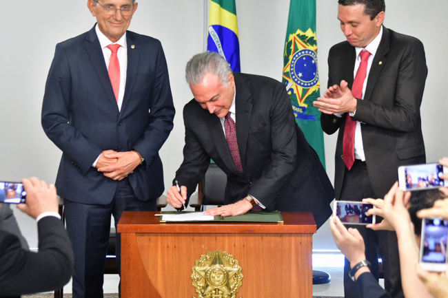 The photo, taken on June 26, 2018, shows Brazilian President Michel Temer signing a bill to recognize August 15th as National Chinese Immigration Day. [Provided to China Plus]