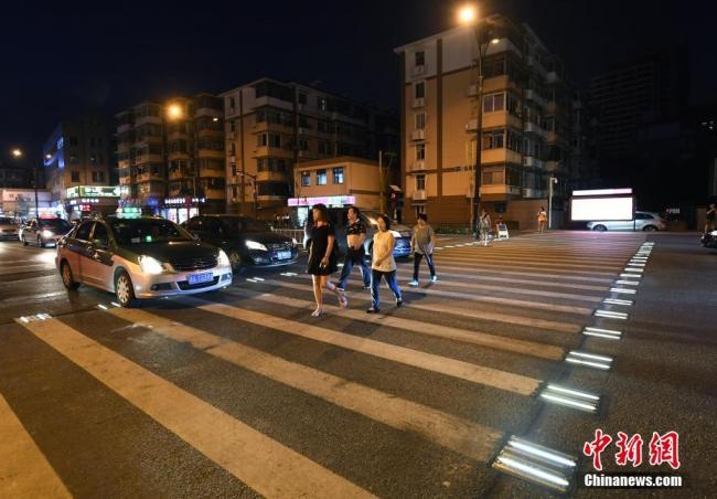 Pedestrians walk across the intelligent zebra crossing that lights up at night when it's used by pedestrians in Hangzhou, Zhejiang Province, on Monday, June 25, 2018. [Photo: Chinanews.com]